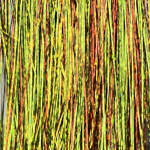 Strands of holographic flashabou in firetiger color, combining vibrant green, yellow, and orange tones for high-visibility streamer and predator fly patterns.